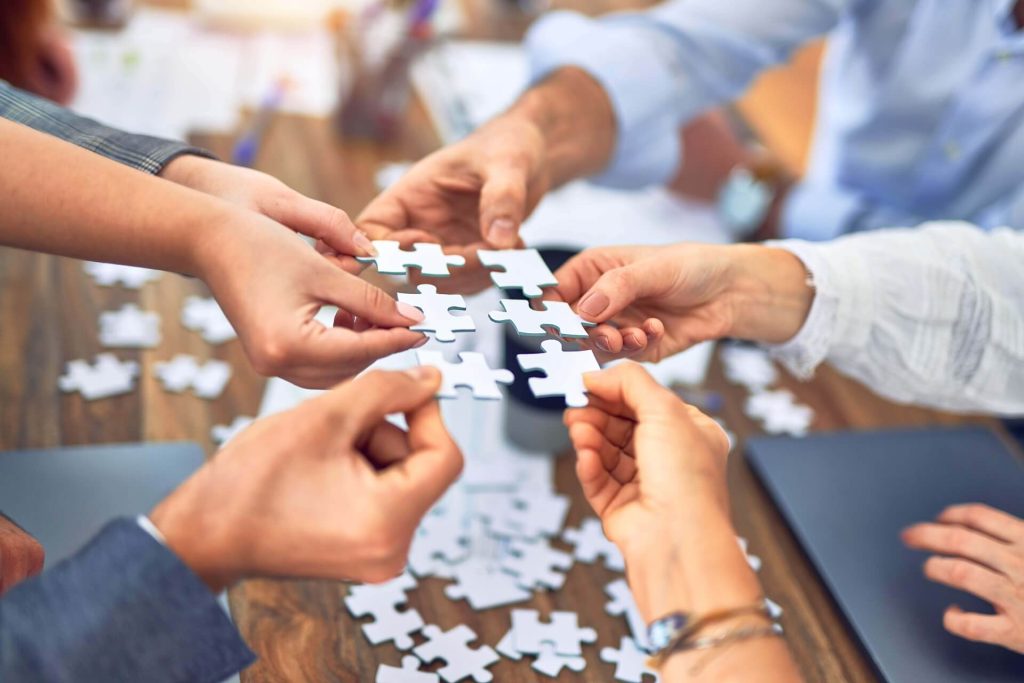ragazzi con in mano dei pezzi di puzzle e i restanti sono appoggiati sul tavolo