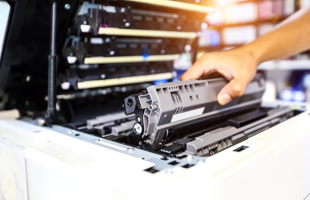 la mano di un uomo sta estraendo il toner esausto da una stampante