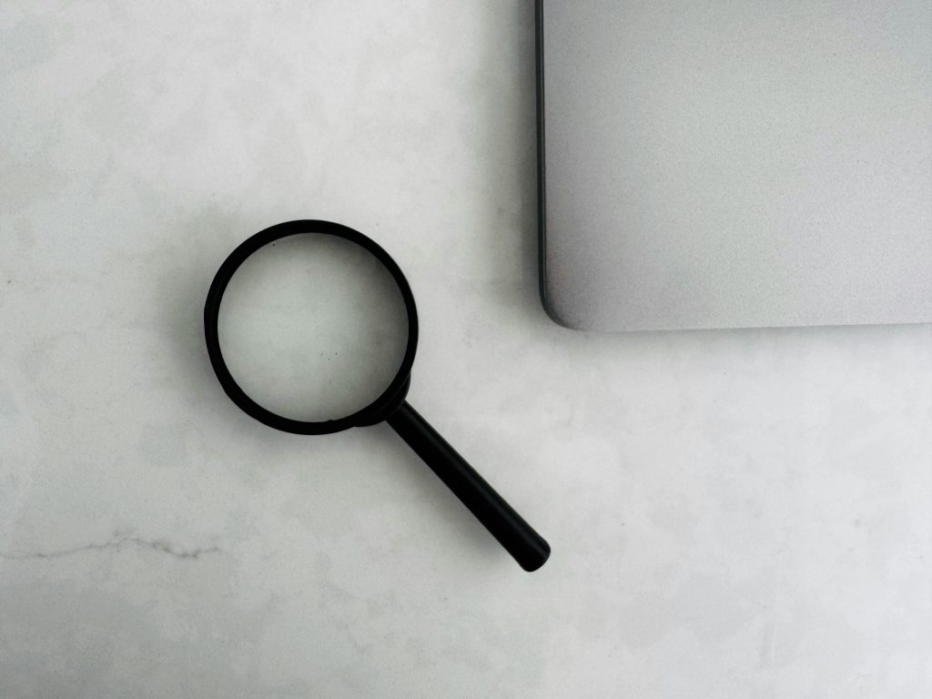 Lente d'ingrandimento accanto a un laptop: analisi del sistema di stampa aziendale